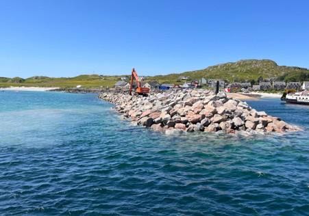 Excavator placing rock armour along the breakwater
