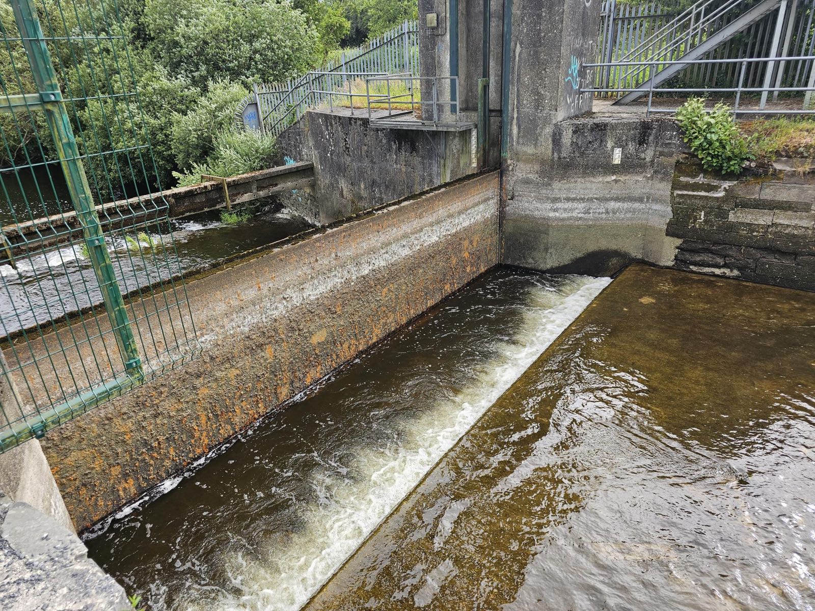Weir sluice with water flowing over the repaired sill